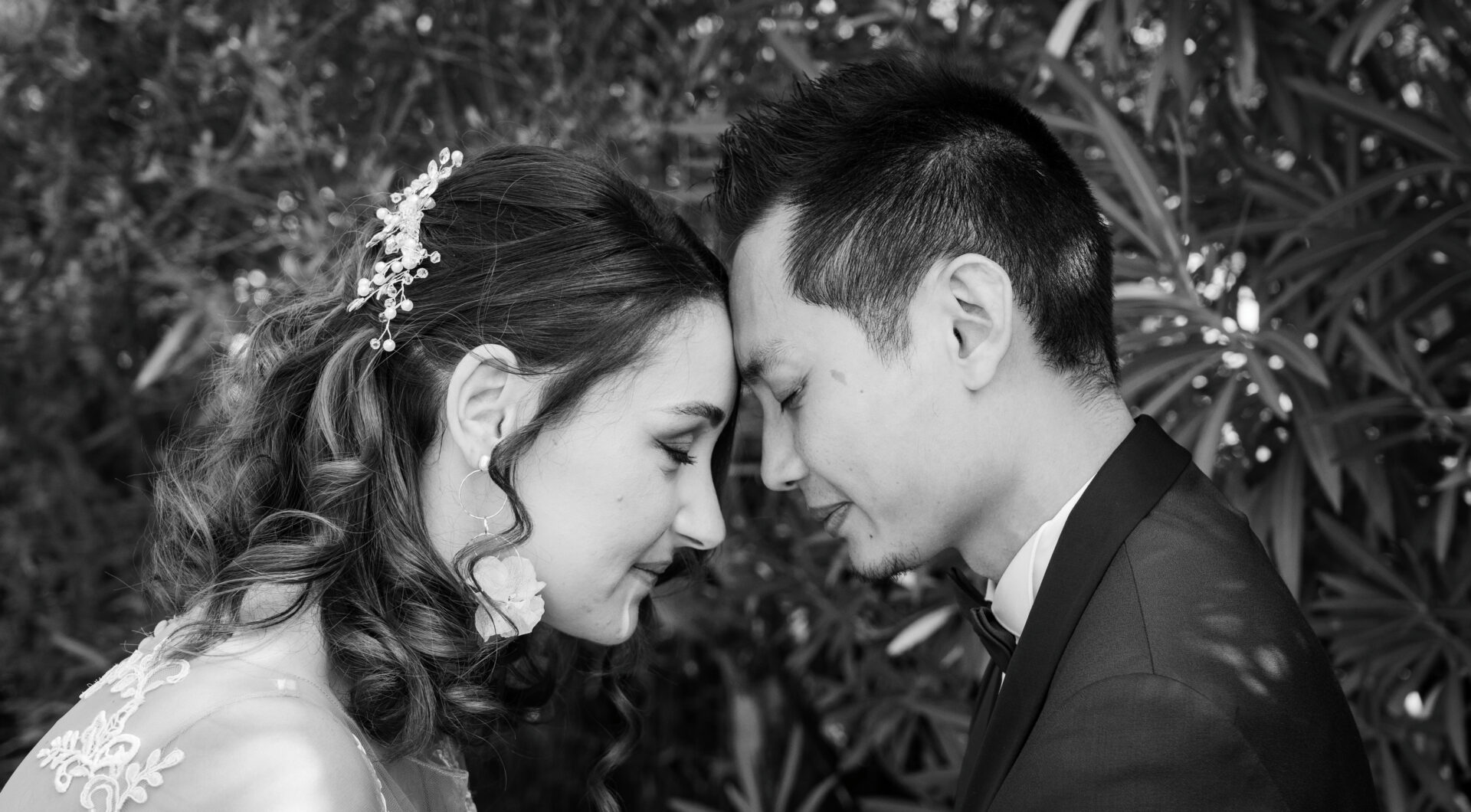 Photographie de mariage en noir et blanc d'un couple tête contre tête.